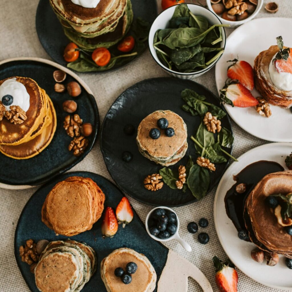A tempting selection of pancakes with berries, nuts, and fresh vegetables.